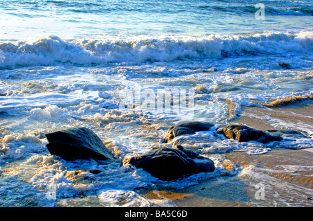 Wellen an einem tropischen Strand waschen sanft über Felsen eingebettet im sand Stockfoto