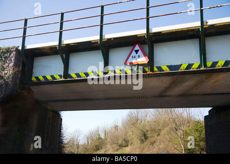 Blick unter einer niedrigen Eisenbahnbrücke über eine Straße.  Christchurch, Dorset. VEREINIGTES KÖNIGREICH.  Schaden Sie durch hohen Fahrzeugen zeigt sich an mehreren Stellen. Stockfoto