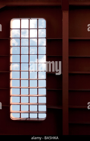 Blick auf blauen Himmel mit Wolken durch Metallgitter. Stockfoto