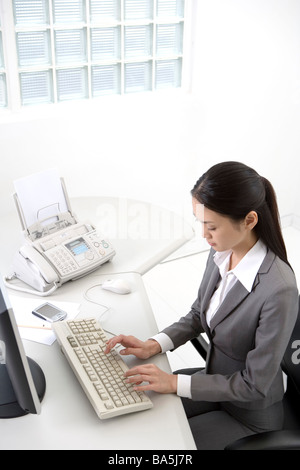 Erhöhte Ansicht der Geschäftsfrau, die Sie am Schreibtisch Seitenansicht eingeben Stockfoto
