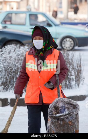 Eine Kehrmaschine trägt eine Gesichtsmaske gegen die schrecklichen Luftverschmutzung in der Stadt Harbin in Nordchina Stockfoto