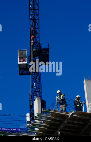 Digitale Fotokamera.  Ein Kran und zwei Bauherren stehen dahinter auf einer Plattform. Stockfoto