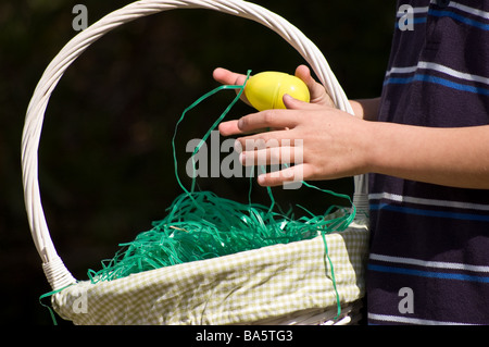 Ein kleiner Junge, ein Easter Egg in einem Korb ablegen Stockfoto