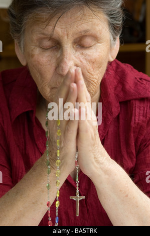 Eine ältere Frau mit ihren Rosenkranz beten Stockfoto