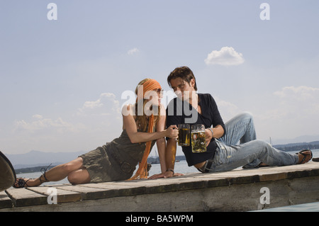 Meer Brücke paar Blick-Kontakt Bier Getränke Beulen keine Eigenschaft Version Serie Menschen Holz-Brücke sitzen Biertrinken Ruhe Erholung Stockfoto