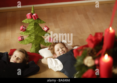 Gebiert zwei Lächeln Boden Lügen Weihnachtsdekoration Christian-Baum Geschenke Adventskranz Kerzen Burns Serie Menschen Kinder Stockfoto