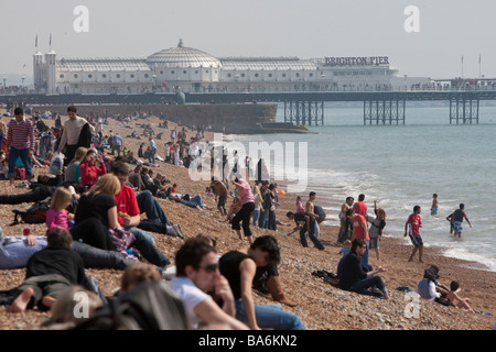 Urlauber am Strand von Brighton, Palace Pier im Hintergrund, Brighton, Ostern Bank Holiday Montag Stockfoto