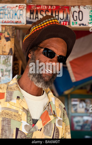 David 'Watusi' Wade, ein Reggae-Sänger mit einem Rasta-Stil-Hut, lächelt, während er eine Sonnenbrille und ein lebhaft gemustertes Hemd trägt Stockfoto