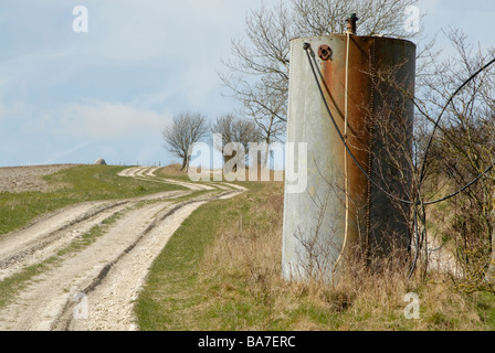 Alten genieteten galvanisierten Stahltank mit Schläuchen neben kalkhaltigen Feldweg auf den South Downs, nr Cocking, West Sussex, England Stockfoto