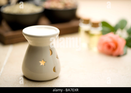 Ölbrenner mit Rose und Glasflaschen im Hintergrund Stockfoto