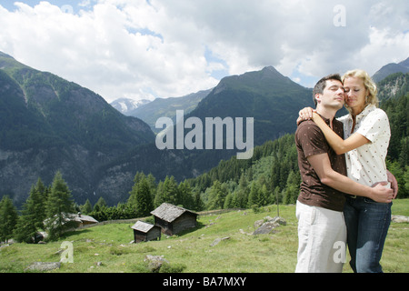 Junges Paar umarmen einander auf Alp, Heiligenblut, Nationalpark Hohe Tauern, Kärnten, Österreich Stockfoto