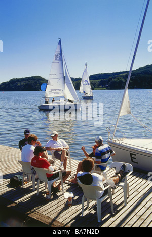 Eine Gruppe von Menschen sitzen auf einem Steg am See, Segelboote im Hintergrund, Baldeney See, Essen, Ruhr-Tal, Ruhr, Northr Stockfoto