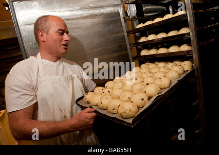 Ein Bäcker Ostern UK traditionelle Hot Cross Buns vorbereiten - unter die angehobenen Brötchen aus dem wärmenden Schrank vor dem Backen Stockfoto