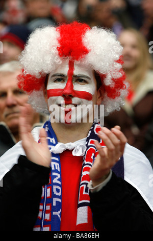 Ein England-Fußball-Fan mit einem gemalten Gesicht und tragen eine bunte Perücke auf den Rängen vor einem Spiel Stockfoto