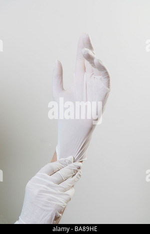 Des Arztes Hände tragen weiße Kautschuk OP-Handschuhe Stockfoto