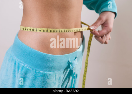 Junge Frau messen Taille mit Maßband Stockfoto