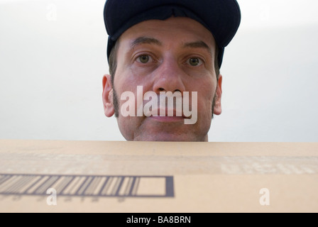 Porträt von ein Postbote mit Kappe hält eine Paket Stockfoto