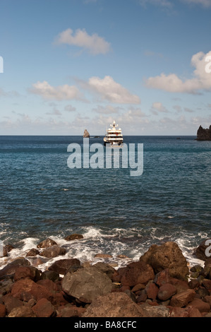 Großen Aron vor Anker in Wells Bucht vom Ufer mit Felsen im Vordergrund und Diamond Rock hinter Stockfoto