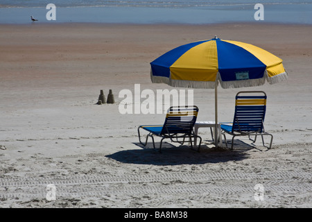 Zwei einsame Sandburgen sitzen vor zwei leere Stühle am Strand, während Spring Break markieren einen Abwärtstrend in der Wirtschaft Stockfoto