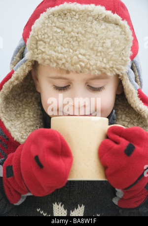 Junge in warme Mütze trinken heißen Schokolade Stockfoto