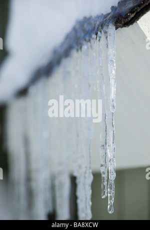 Eiszapfen hängen von Dachtraufe Stockfoto