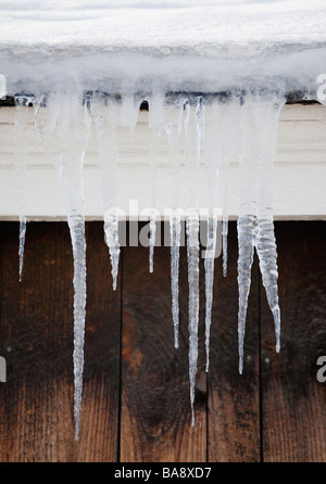 Eiszapfen hängen von Dachtraufe Stockfoto