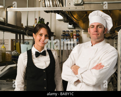 Koch und Kellnerin posiert in der Küche des Restaurants Stockfoto