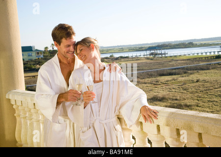 Brautpaar mit Champagner auf Balkon im Bademantel Stockfoto