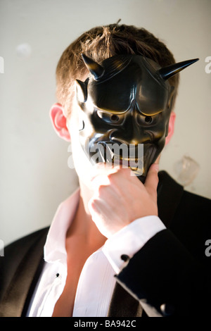Porträt des jungen Mann im Smoking hält Maskerade Maske Stockfoto