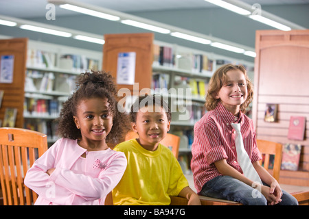 Drei Grundschulkinder lächelnd in der Schulbibliothek Stockfoto