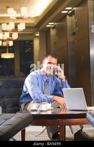 Geschäftsmann, sitzen in der Hotel-Lobby mit Handy Stockfoto