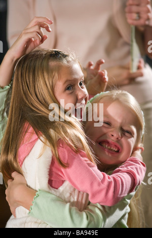 Zwei Grundschule Mädchen umarmen und Lachen in Bibliothek Stockfoto