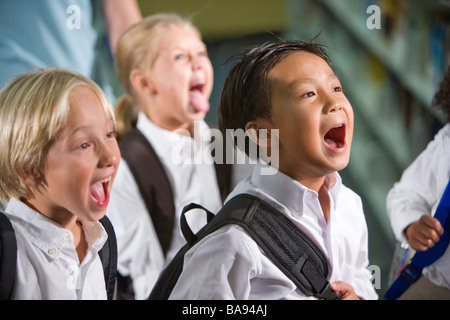 Asiatische und kaukasischen Grundschüler schreien in Bibliothek Stockfoto