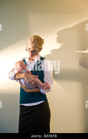 Junge Geschäftsfrau Holding schreiendes Baby in armen Stockfoto