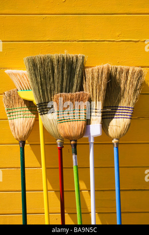 Besen, die gelbe Wand gelehnt Stockfoto