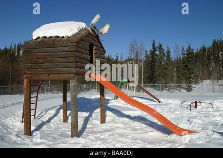 Ein Blockhaus und Folie auf einem Spielplatz in der First Nation Ortschaft Old Crow, Yukon Territorium, Kanada. Stockfoto