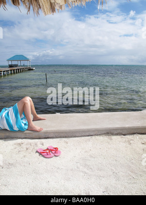Junge Frau auf einem Deich mit rosa Sandalen Stockfoto