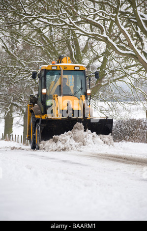 JCB wird verwendet, um eine Schnee bedeckt Straße auf dem Land in England im winter Stockfoto