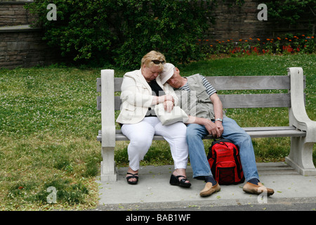 Älteres Ehepaar Nickerchen ein Katze auf einer Bank an der Brooklyn Botanic Gardens in Brooklyn New York Stockfoto