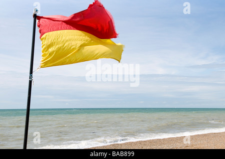 Ein Rettungsschwimmer auf Pflicht Flagge weht im Wind am Strand von Brighton, England Stockfoto