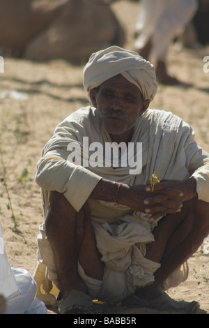 Indischen Mann in traditioneller Kleidung, hocken auf dem Boden bei Pushkar Camel fair Stockfoto