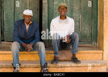 Zwei ältere Männer in Kappen sitzen auf den Stufen eines Eigenheims in Trinidad, Kuba. Stockfoto