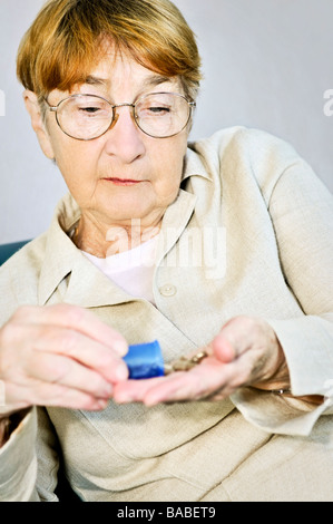 Ältere Frau, die Medikamente aus Pille Flasche gießen Stockfoto