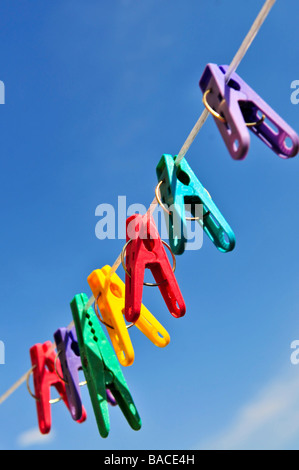 Bunte Wäscheklammern auf Linie gegen blauen Himmel Stockfoto