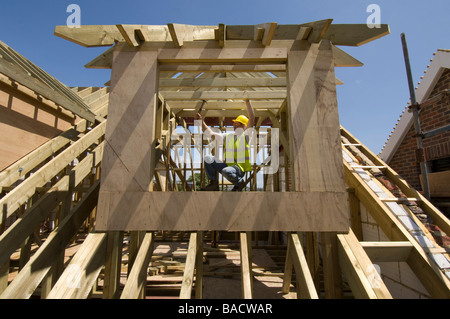 Ein Baumeister, Bau einer Dachgaube auf dem Dach eines neuen Hauses. Stockfoto