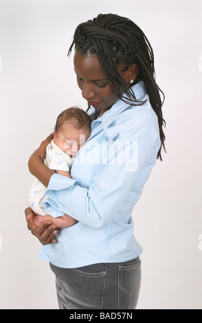 Eine schöne afroamerikanische Frau, liebevoll mit einem weißen oder gemischten Rennen neugeborenes Kind Stockfoto