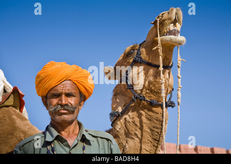 Mann steht neben einem Kamel an Osian Camel Camp, Osian, Rajasthan, Indien Stockfoto