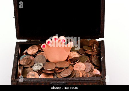 Kleine Kunststoff Hand in einer kleinen Schatztruhe voller Münzen Stockfoto