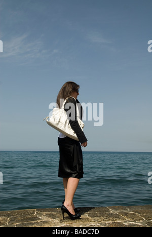 Business-Frau stehend am Meer tragen einer Handtasche Stockfoto