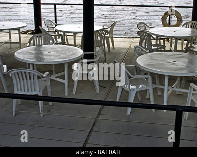 Picknick-Tische und Stühle auf einem Dock nahe dem Fluss weiße Plastikstühle und Metall weiße Runde Tische mit Geländer rund um Satz Stockfoto